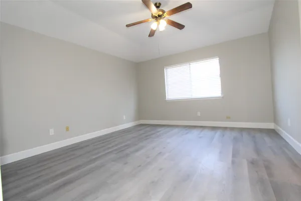 a view of an empty room with window and wooden floor