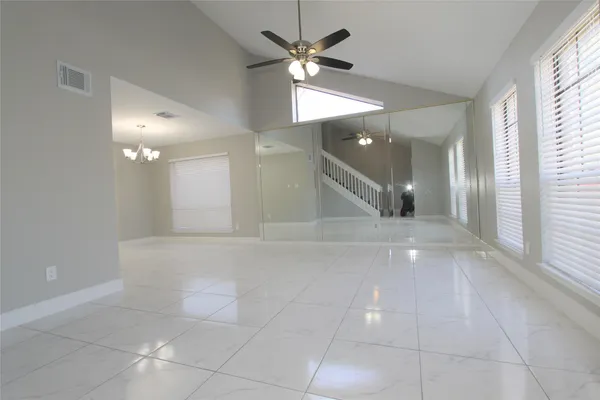 a view of a hallway with a chandelier fan and windows