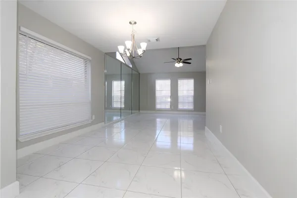 a view of an empty room with window and chandelier fan