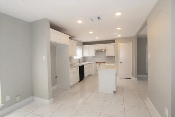 a kitchen with white cabinets appliances a sink and a window