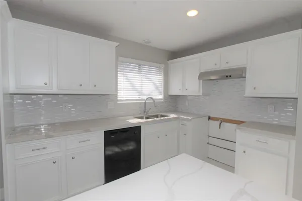 a kitchen with white cabinets appliances a sink and a window