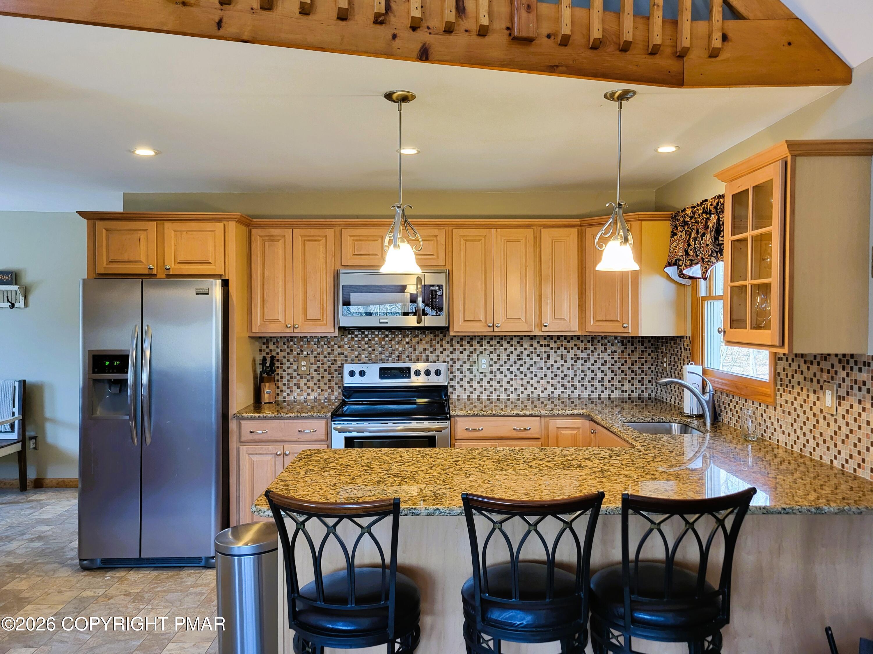 155 Clifton Drive Bushkill, PA 18324 - Photo 11 of 75 a kitchen with stainless steel appliances kitchen island granite countertop a table chairs and a refrigerator