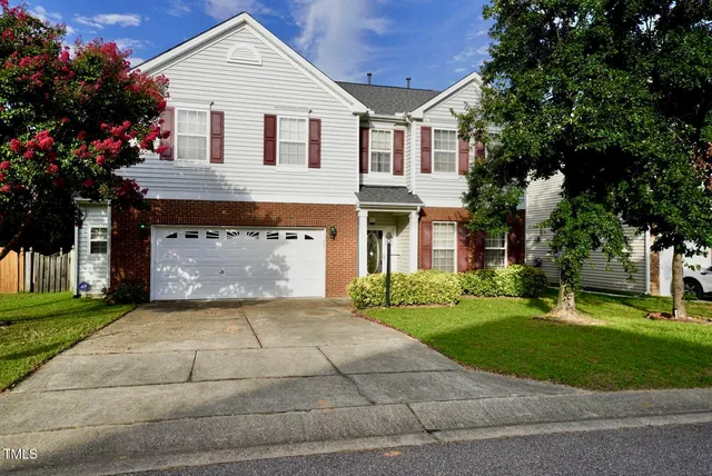 a view of a white house next to a yard and a large tree