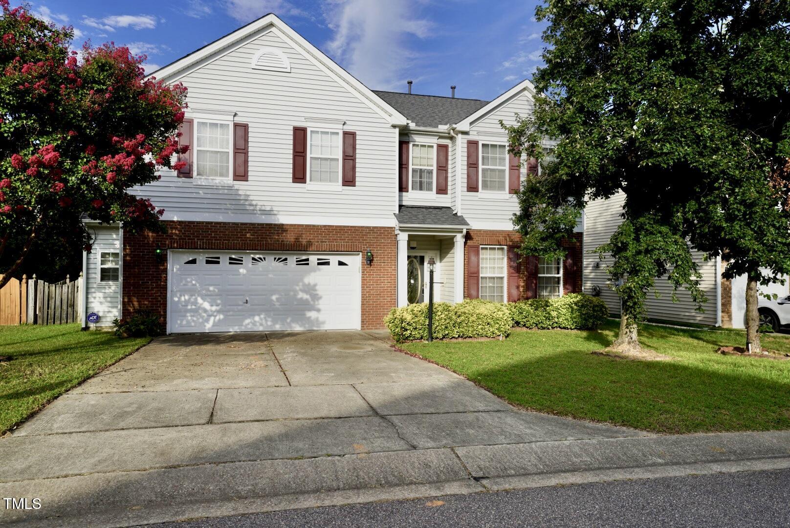 a view of a white house next to a yard and a large tree