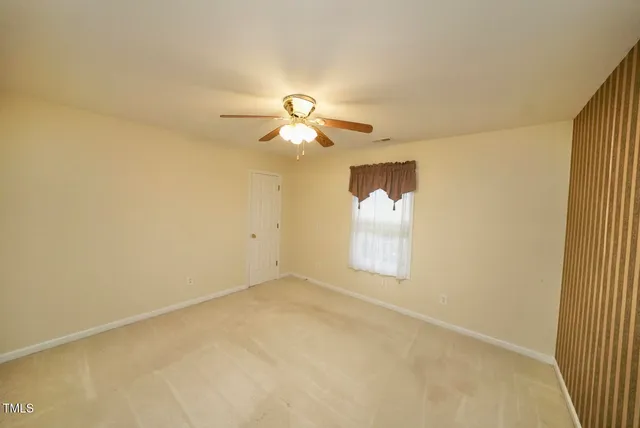 an empty room with a window and a ceiling fan