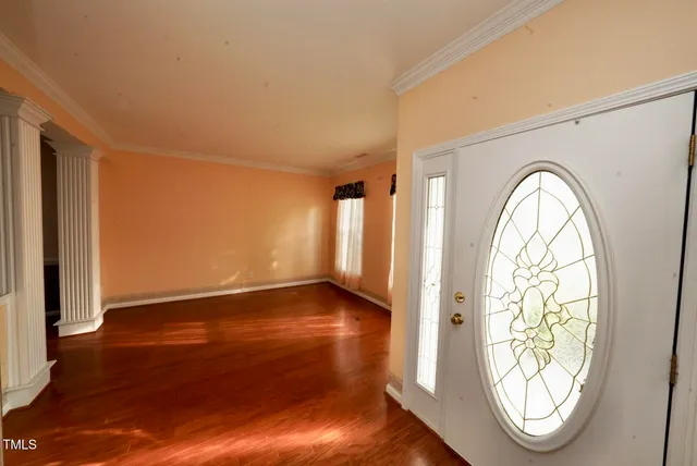 an empty room with wooden floor mirror and window