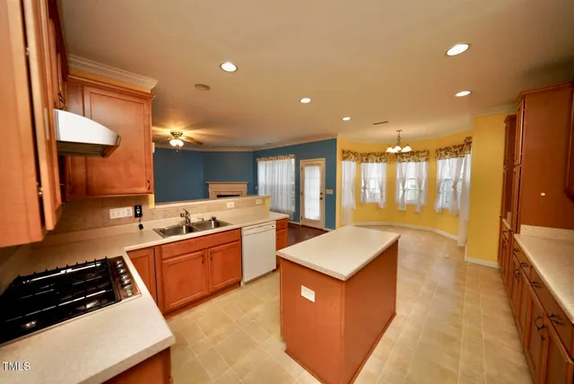 a large kitchen with stainless steel appliances a large counter top a stove a sink a refrigerator and a dining table