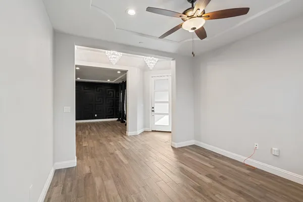 a view of an empty room with wooden floor and a ceiling fan