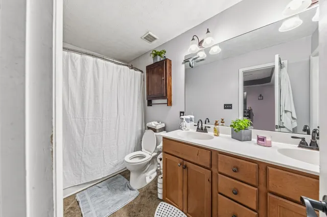 a spacious bathroom with a granite countertop sink a toilet and a mirror