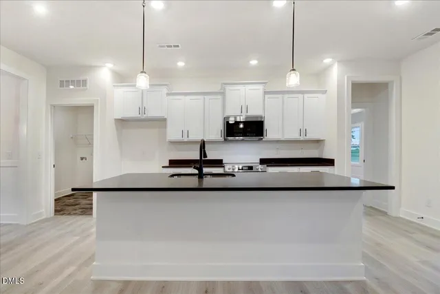 a kitchen with kitchen island a sink appliances and cabinets
