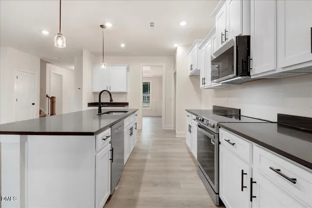 a kitchen with granite countertop a sink cabinets and stainless steel appliances