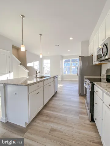 a large kitchen with stainless steel appliances kitchen island granite countertop a stove a sink and a wooden floors