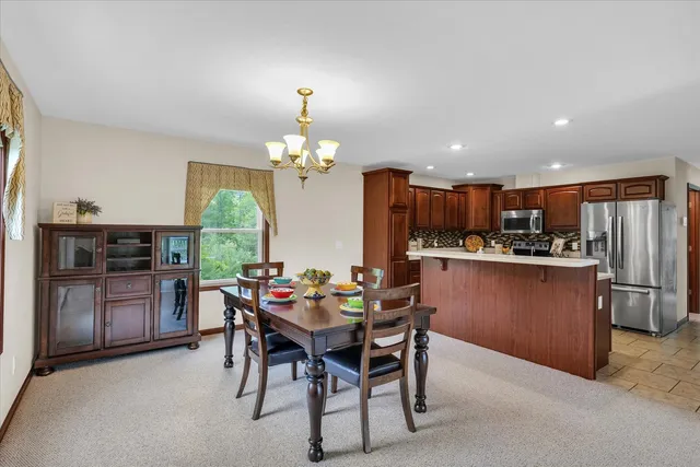 a dining room with wooden floor a chandelier a wooden table and chairs