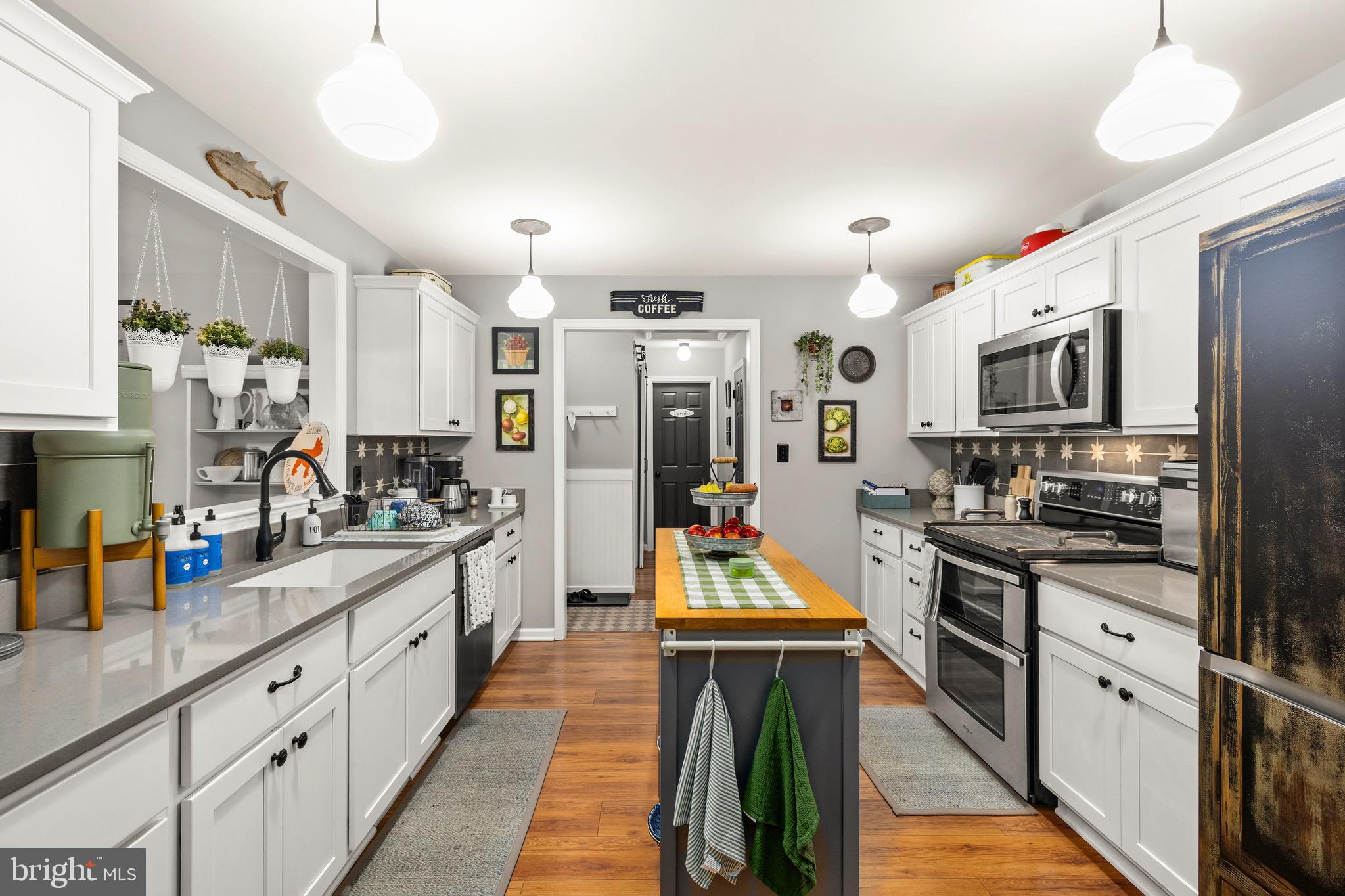 30367 Old Locust Grove Locust Grove, VA 22508 - Photo 22 of 36 a kitchen with stainless steel appliances kitchen island granite countertop a refrigerator a stove top oven a sink dishwasher and white cabinets with wooden floor
