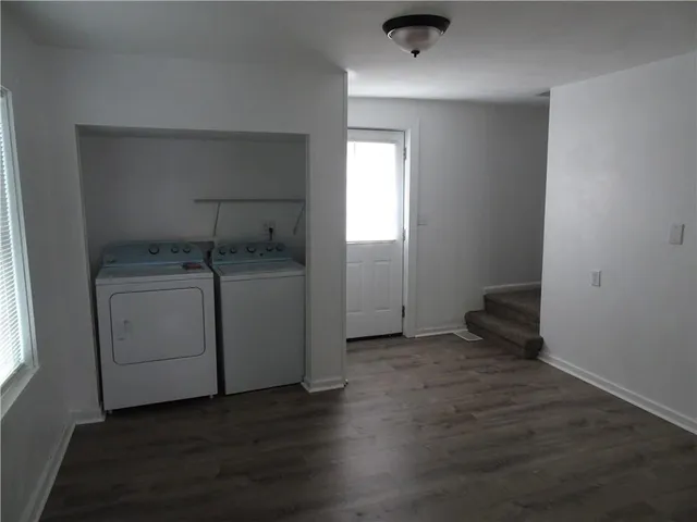 an empty room with wooden floor cabinet and windows