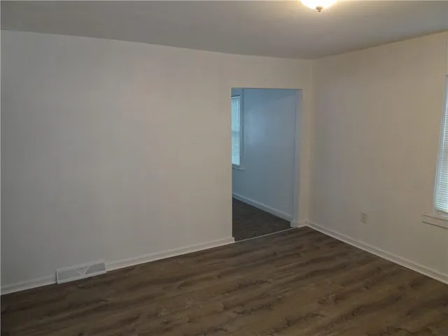 an empty room with wooden floor cabinet and windows