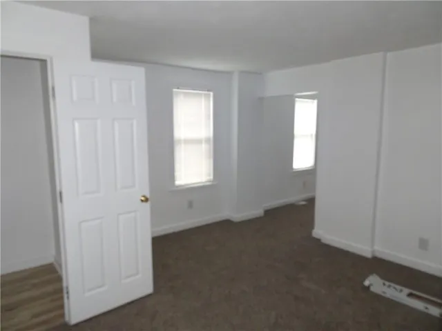 a view of an empty room with closet and a window