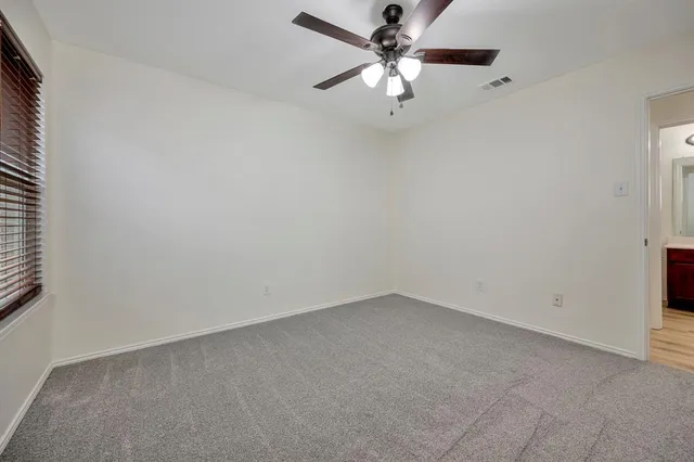 an empty room with a chandelier fan and windows