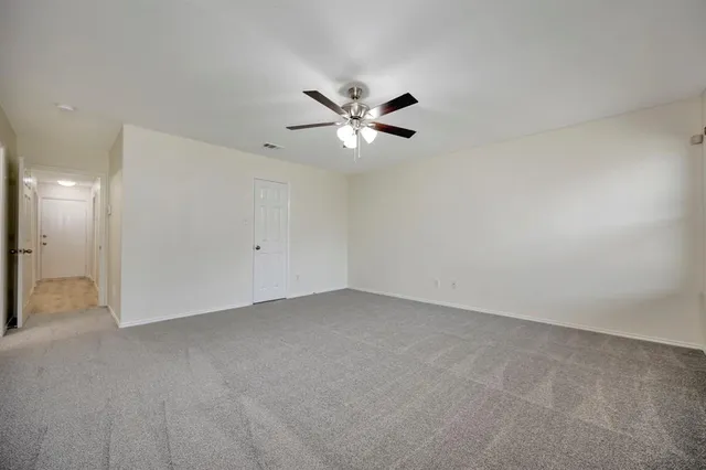 an empty room with closet and a ceiling fan