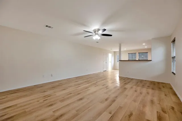 a view of a big room with wooden floor and a ceiling fan