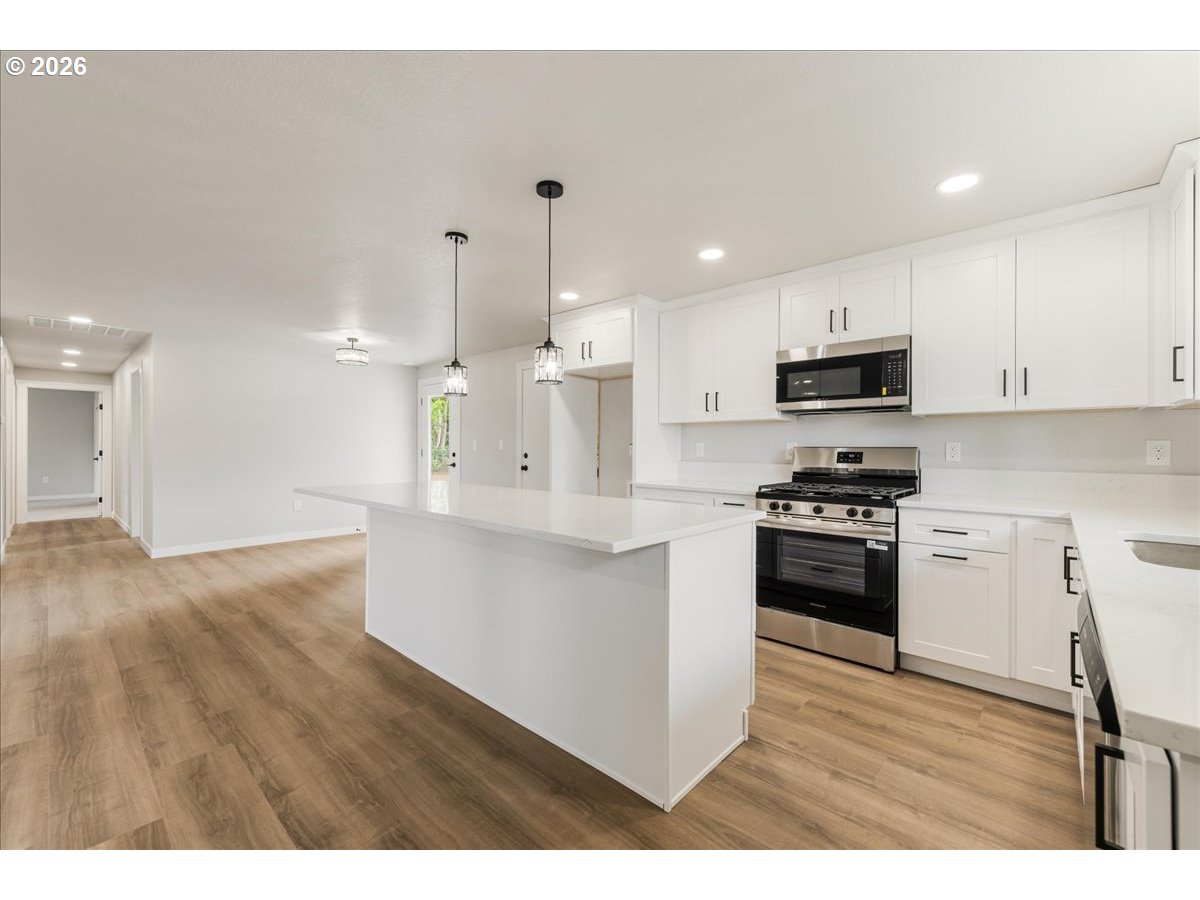 795 Northwest 6th Avenue Canby, OR 97013 - Photo 12 of 40 a kitchen with stainless steel appliances kitchen island granite countertop a stove a sink a refrigerator and white cabinets with wooden floor