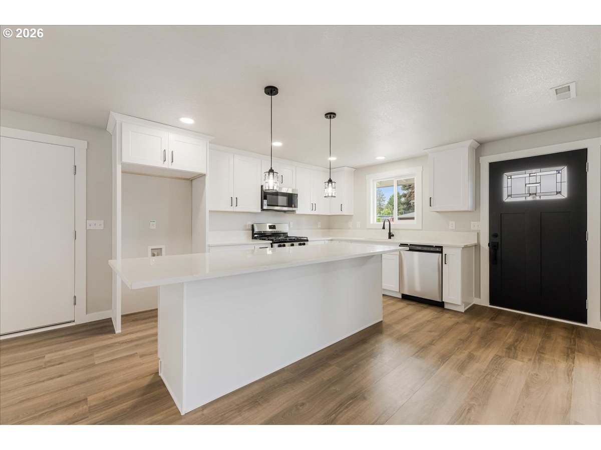 795 Northwest 6th Avenue Canby, OR 97013 - Photo 13 of 40 a kitchen with stainless steel appliances cabinets a sink and a wooden floor