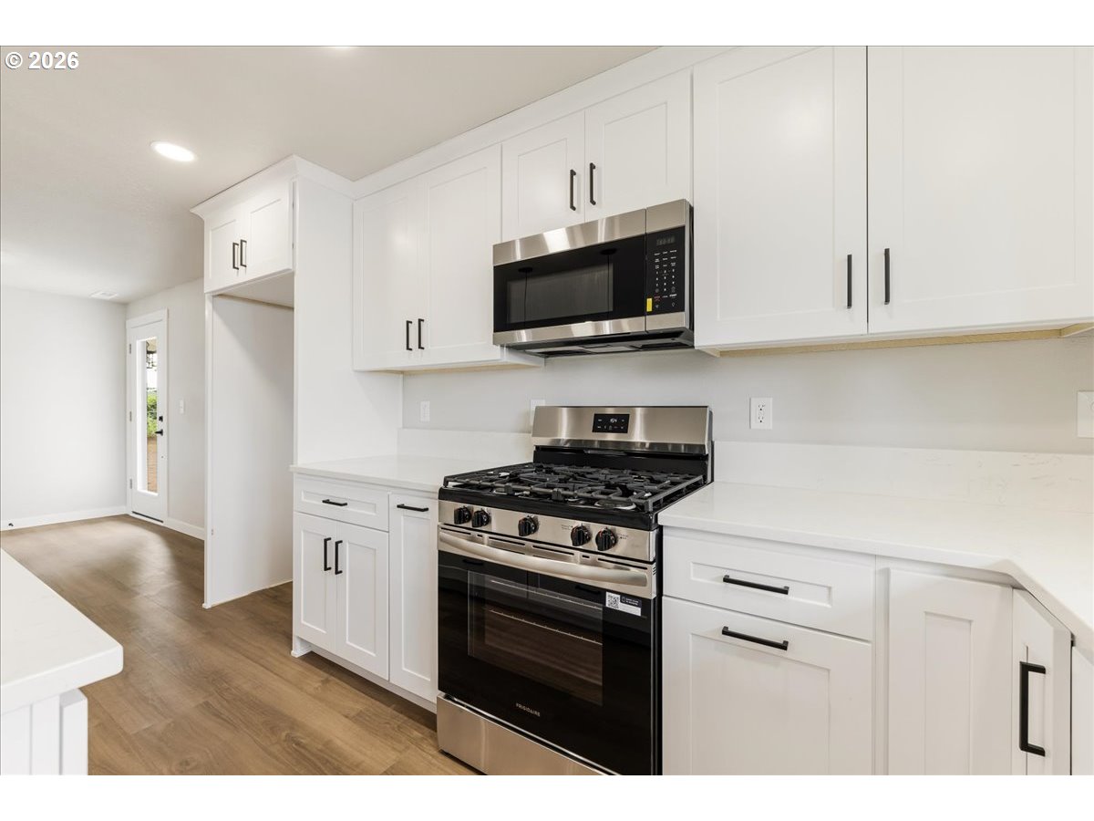795 Northwest 6th Avenue Canby, OR 97013 - Photo 16 of 40 a kitchen with stainless steel appliances granite countertop a sink dishwasher a stove and a microwave oven with cabinets