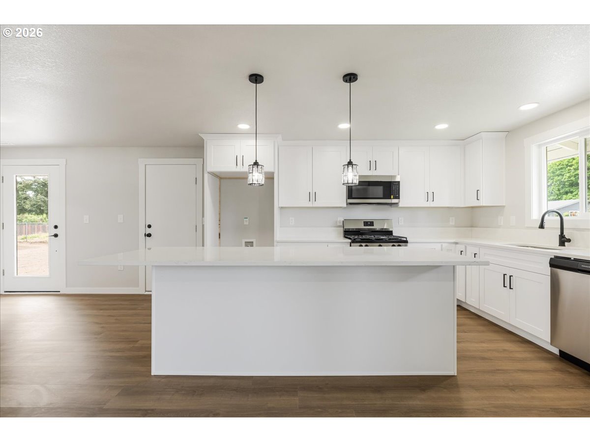 795 Northwest 6th Avenue Canby, OR 97013 - Photo 17 of 40 a kitchen with stainless steel appliances granite countertop a stove a sink dishwasher and a white refrigerator with wooden floor