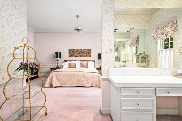 a spacious bedroom with a bed a chandelier and dresser