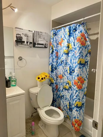 a white toilet sitting next to a sink and a shower curtain