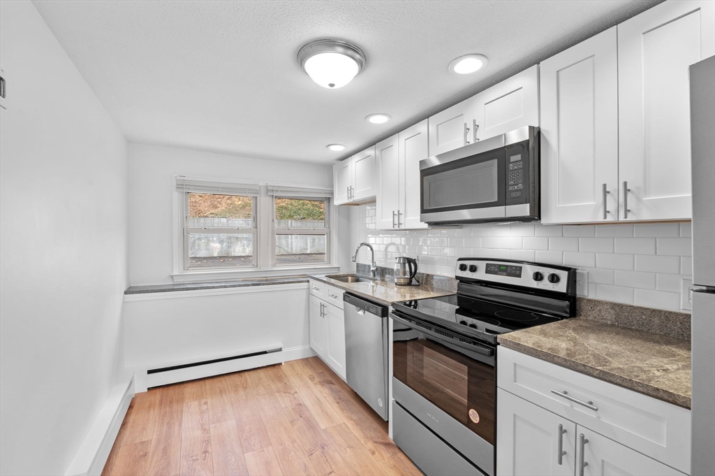 121 Cambridge Road, Unit 2 Woburn, MA 01801 - Photo 9 of 23 a kitchen with granite countertop cabinets stainless steel appliances and a counter space