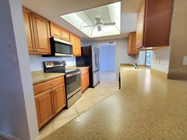 a kitchen with stainless steel appliances granite countertop a sink a stove top oven a chimney cabinets and a dining table