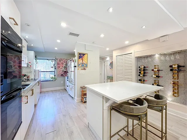 a kitchen with stainless steel appliances kitchen island granite countertop a stove a refrigerator a oven a sink with island and chairs