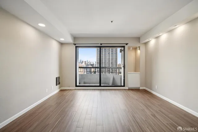 a view of an empty room with wooden floor and a window