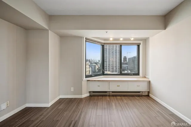 a view of an empty room with wooden floor and a window