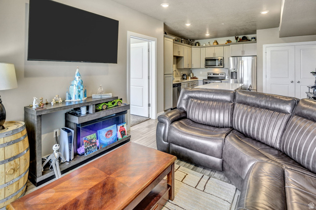 2101 North Main Street, Unit 306 Sunset, UT 84015 - Photo 10 of 22 Open-concept living space featuring a kitchen with stainless steel appliances and light-toned cabinetry, an island with a white countertop, and recessed lighting