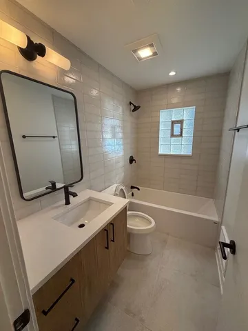 a bathroom with a bathtub sink vanity mirror and toilet