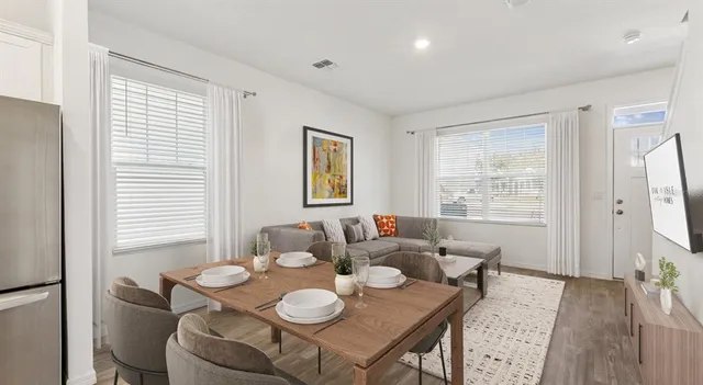 a dining room with furniture a large window and potted plants