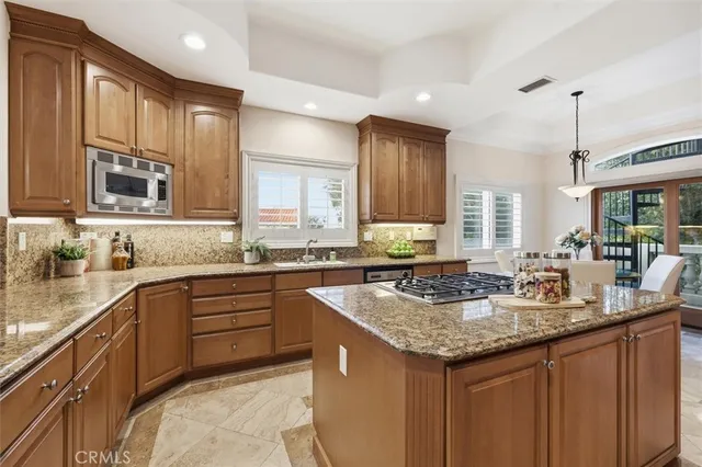 a kitchen with stainless steel appliances granite countertop a sink a stove and a wooden cabinets