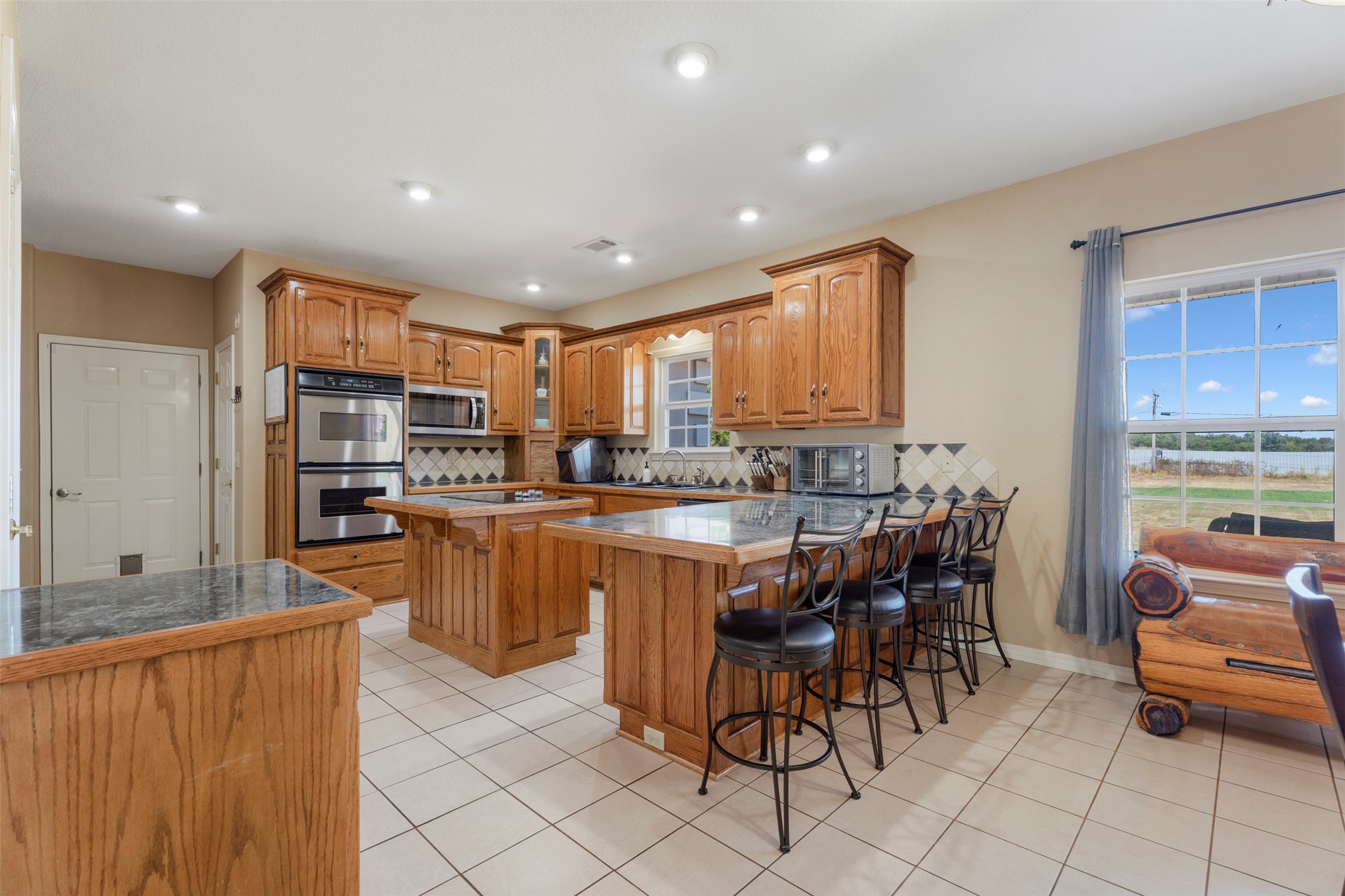 20233 East 570 Road Colcord, OK 74338 - Photo 13 of 39 Kitchen featuring wood cabinetry, stainless steel double ovens, recessed lighting, and tile flooring