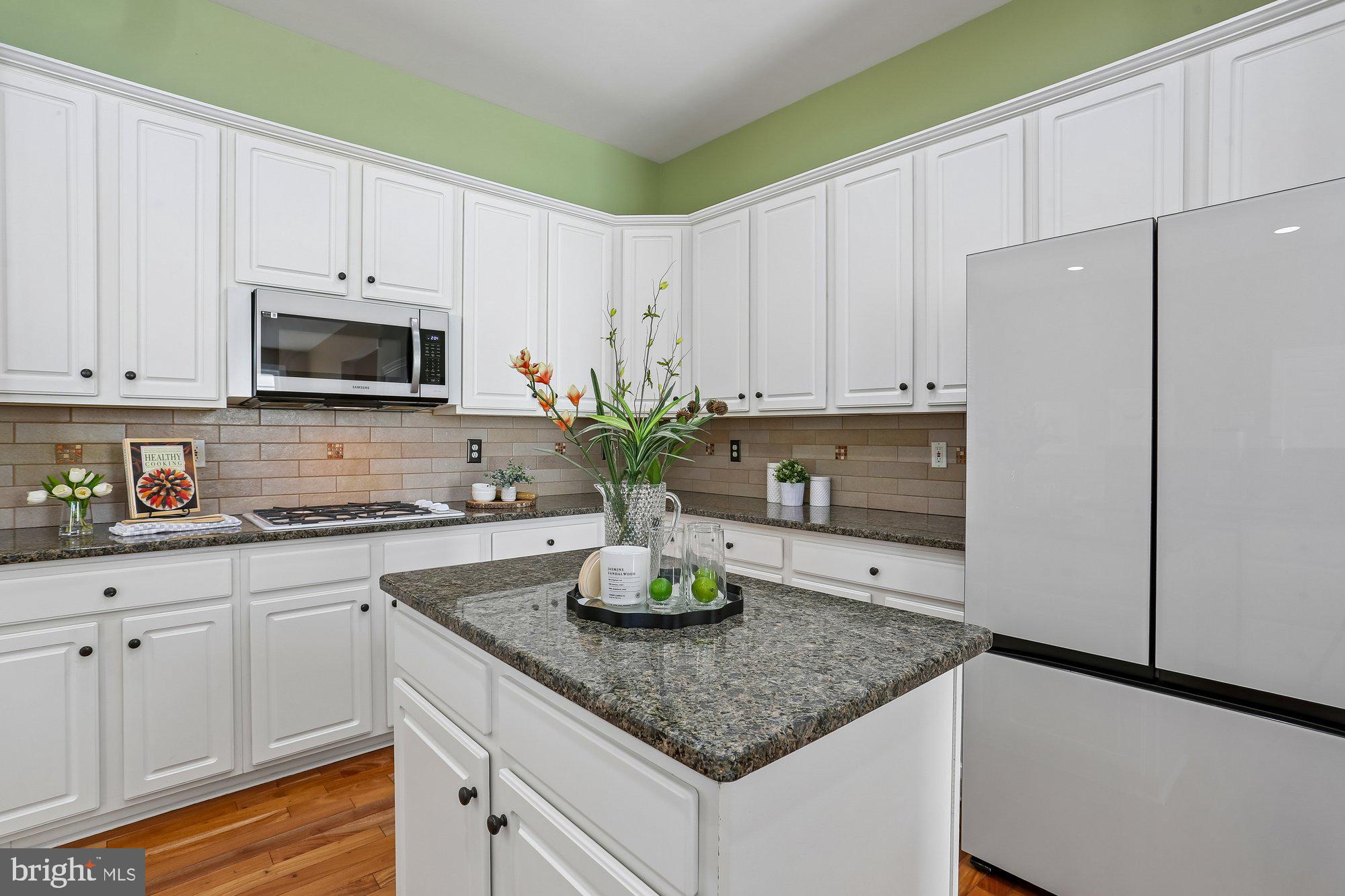 945 Main Street Gaithersburg, MD 20878 - Photo 11 of 57 a kitchen with kitchen island granite countertop white cabinets white appliances a sink and a potted plant