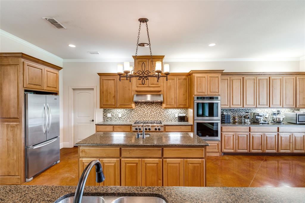 643 County Road 2255 Telephone, TX 75488 - Photo 14 of 40 Kitchen with stainless steel appliances, tasteful backsplash, ornamental molding, dark stone countertops, and brown cabinets