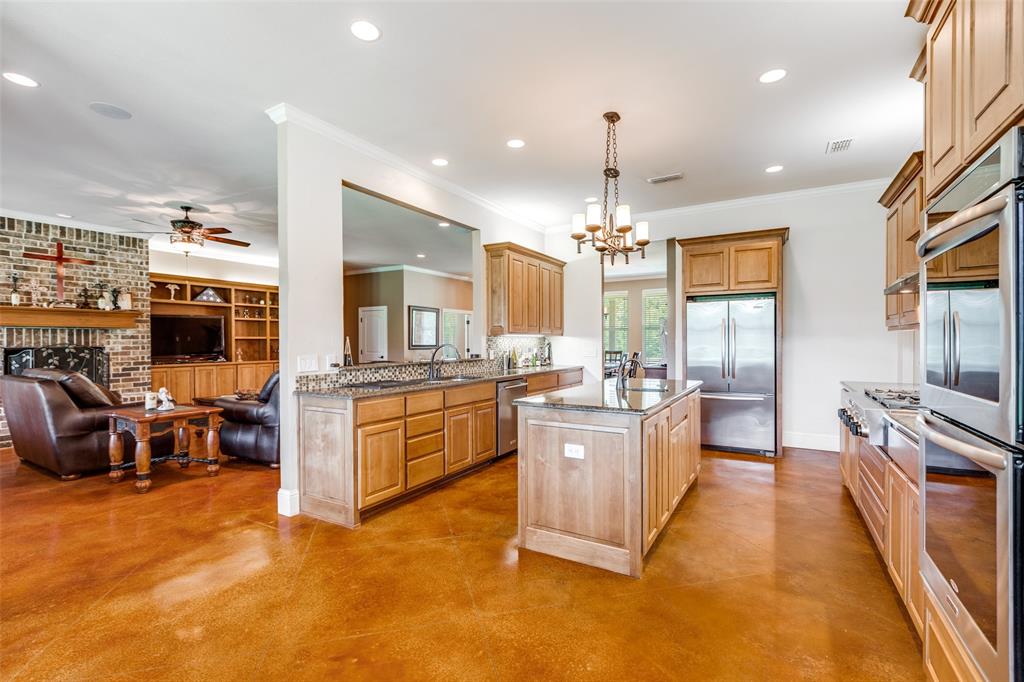 643 County Road 2255 Telephone, TX 75488 - Photo 39 of 40 Kitchen featuring a kitchen island with sink, light stone counters, stainless steel appliances, open floor plan, and concrete flooring