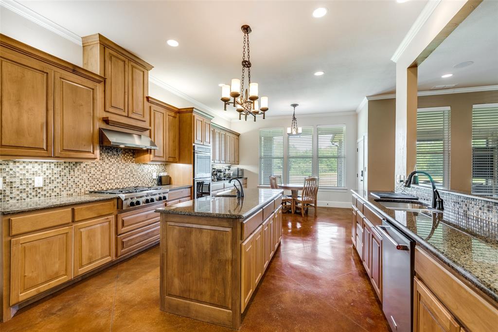 643 County Road 2255 Telephone, TX 75488 - Photo 16 of 40 Kitchen featuring backsplash, ornamental molding, dark stone countertops, brown cabinetry, and decorative light fixtures
