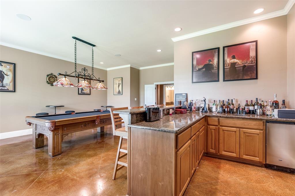 643 County Road 2255 Telephone, TX 75488 - Photo 20 of 40 Indoor wet bar featuring recessed lighting, ornamental molding, dark stone counters, pendant lighting, and brown cabinetry