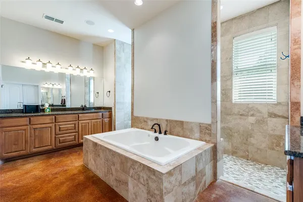 a spacious bathroom with a tub double sink and mirror