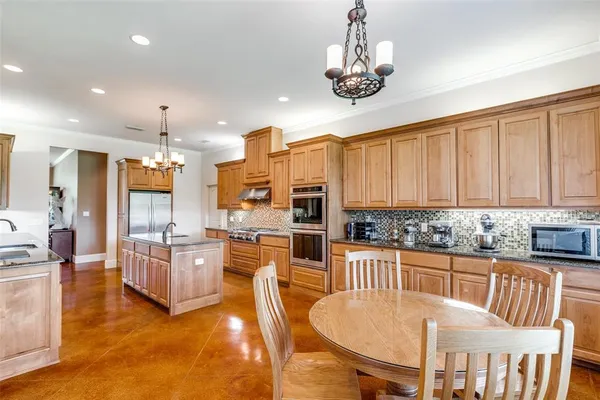 a kitchen with stainless steel appliances granite countertop a stove a refrigerator a kitchen island a dining table and chairs