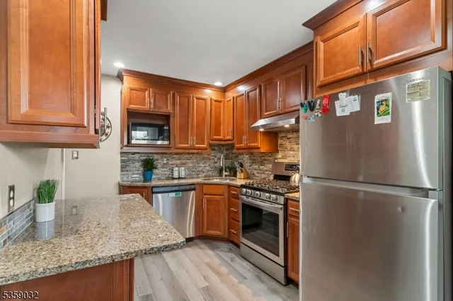 a kitchen with stainless steel appliances granite countertop a refrigerator a stove a sink and a microwave