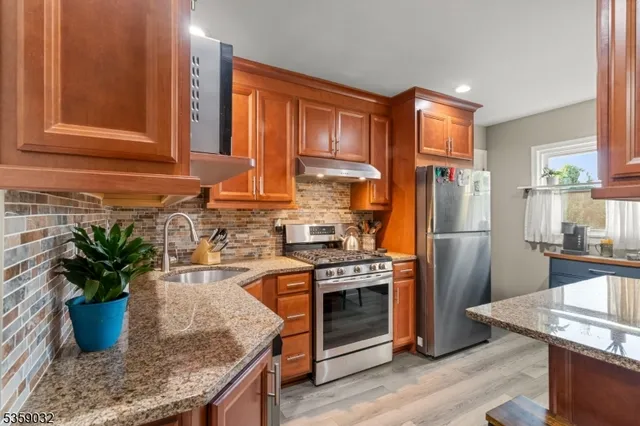 a kitchen with stainless steel appliances granite countertop a sink a stove and a refrigerator