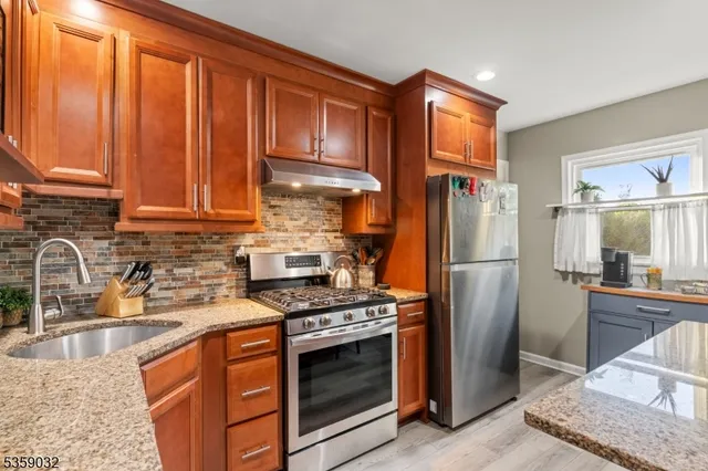 a kitchen with stainless steel appliances granite countertop a refrigerator stove and sink